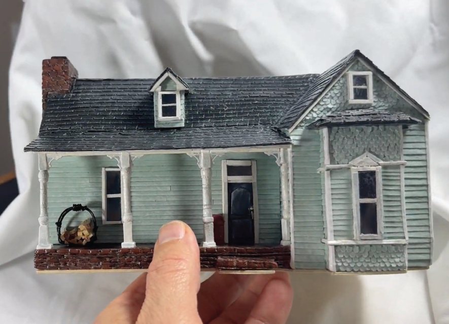 Commission in progress: front view of the Columbia home miniature with porch columns and a firewood basket