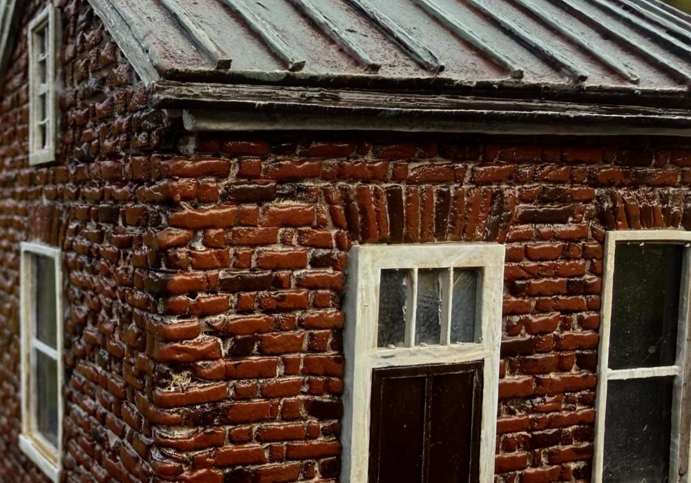 Close-up of the McPhail House miniature's front door, transom window, hand-painted brick and metal roof