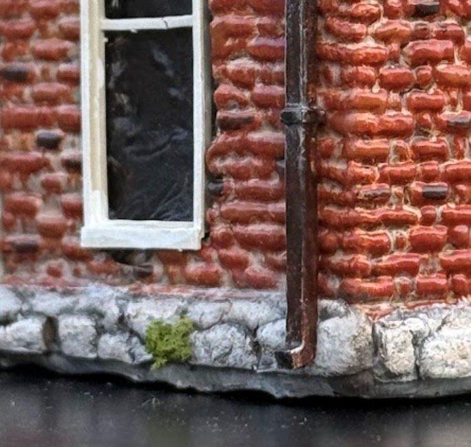 Close-up of the McPhail House miniature's hand-painted brick, window and stone foundation